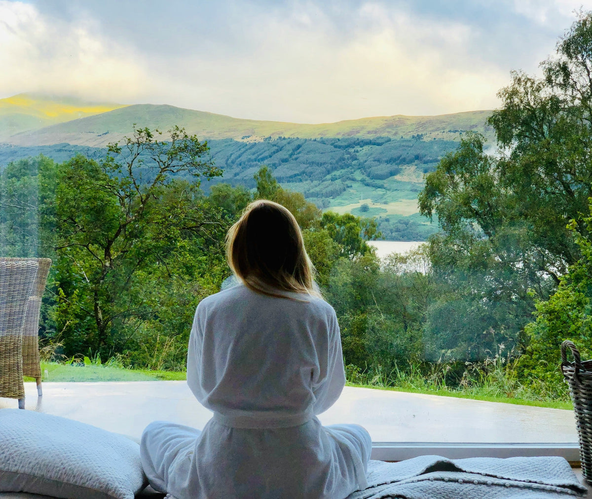 Peaceful woman with radiant, healthy skin smiling in a sunlit lush garden, representing the natural path to rejuvenate stressed skin.