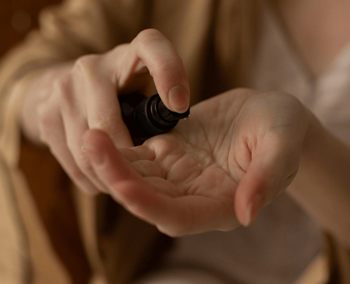 Person applying Halo 42 body oil to their hands, showcasing the product's hydrating and anti-aging properties.