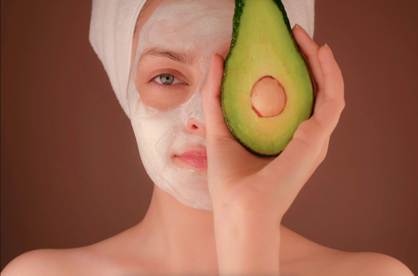 Woman with face mask holding avocado showing the best eye wrinkle product natural skincare ritual